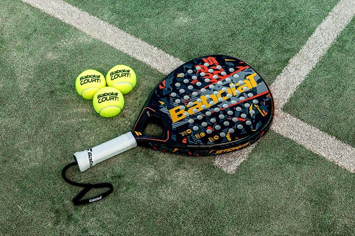 A pala with padel balls beside it